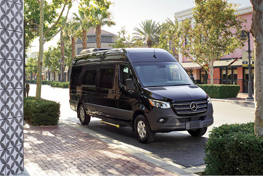 Black Mercedes-Benz Sprinter Passenger Van parked in a downtown shopping district.