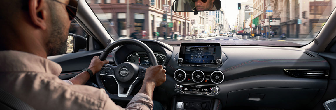 Nissan Sentra interior with driver, infotainment system, and dashboard view