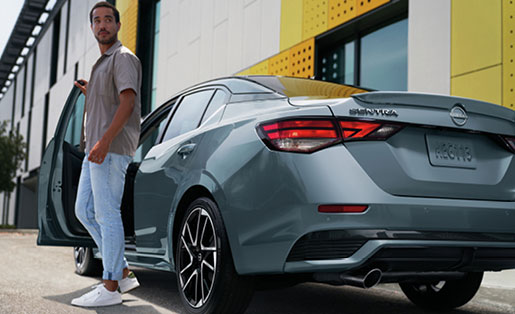 Gray Nissan Sentra sedan with driver standing beside the vehicle