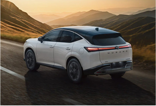 White Nissan Murano SUV driving on a scenic mountain road at sunset