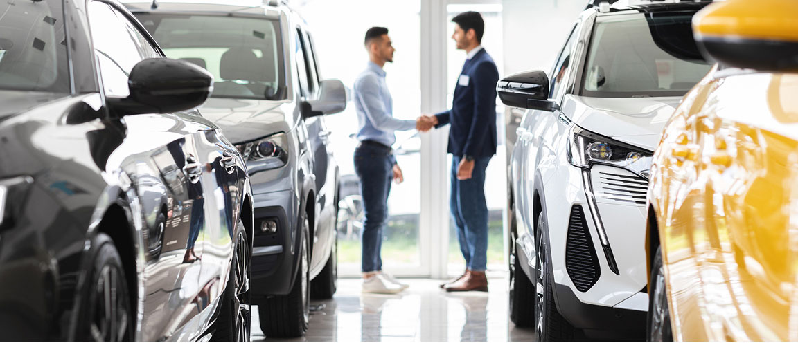 Customer shaking hands with a salesperson inside a car dealership showroom
