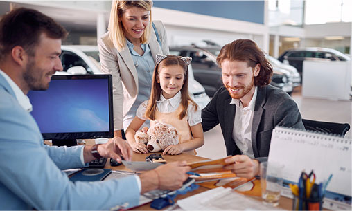 Family reviewing vehicle purchase options with a salesperson at a car dealership