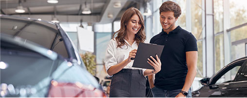 Couple using a tablet while shopping for a vehicle at a dealership