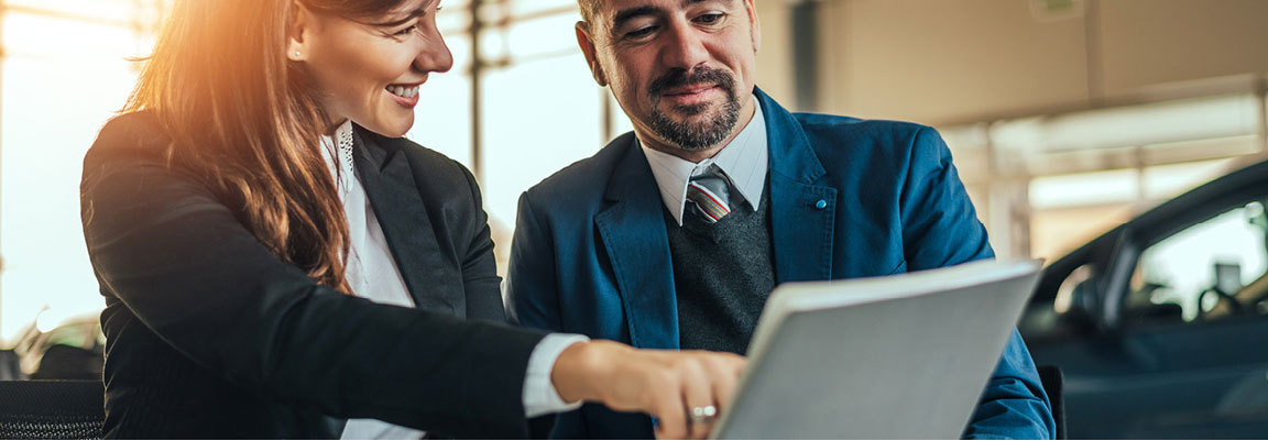 Car dealership professionals reviewing vehicle financing options on a laptop