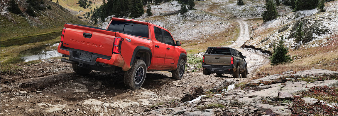 Toyota Tacoma pickup trucks driving off-road on a rugged mountain trail