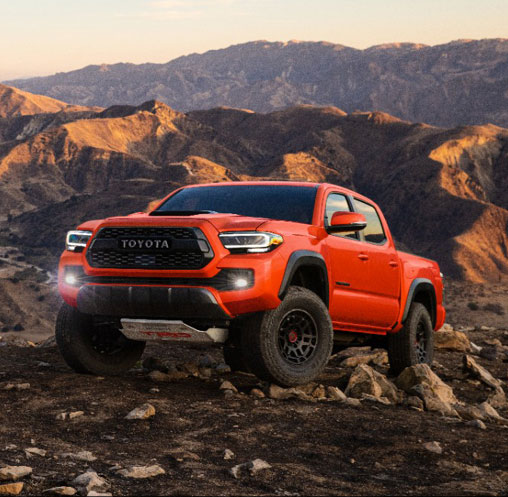 Red Toyota Tacoma off-road pickup truck in a rocky mountain setting