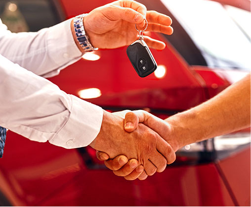 Customer receiving car keys and shaking hands after a vehicle purchase
