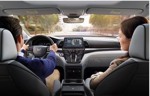 Interior view of the Honda Odyssey cabin featuring driver, front passenger and infotainment display with rear camera technology.