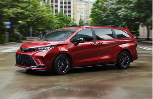 Red Toyota Sienna driving through an urban environment highlighting stylish design and smooth city performance.