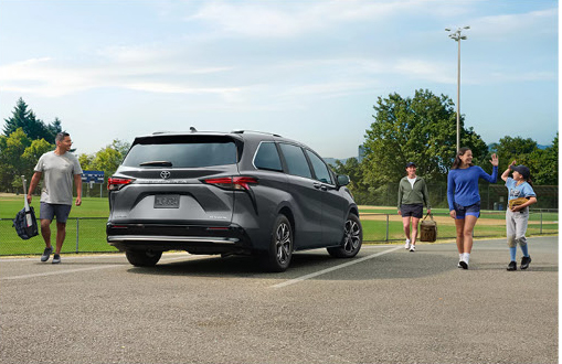 Gray Toyota Sienna parked at a sports field with families loading and unloading passengers for everyday activities.