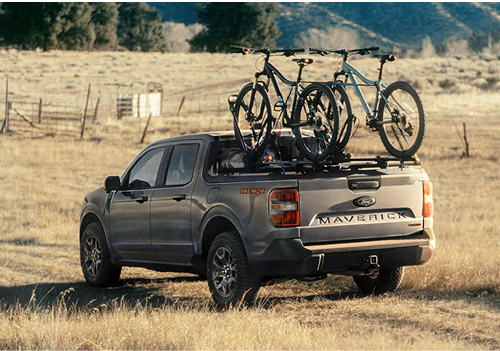 Ford Maverick truck with mountain bikes loaded in truck bed in open field