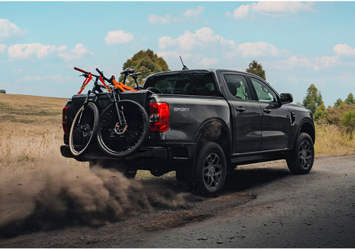 Ford Ranger truck driving on dirt road with bikes mounted on tailgate