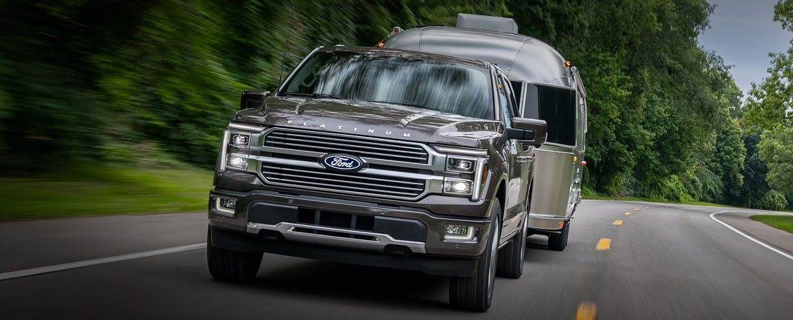Ford F-150 full-size pickup truck towing an Airstream travel trailer on a highway