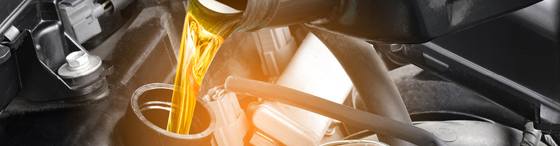Fresh motor oil being poured into a Ford engine during an oil change service