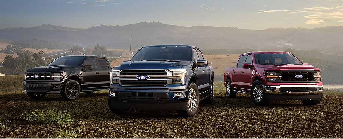 Three Ford F-150 full-size pickup trucks parked in a rural landscape with rolling hills at sunset
