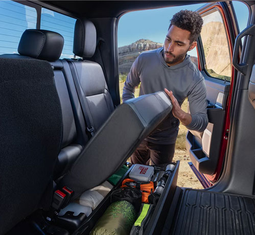 Man lifting the Ford F-150 rear seat to access under-seat storage for tools and outdoor gear