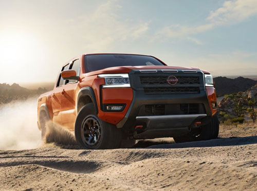 Nissan Frontier midsize pickup truck driving off-road on a dusty desert trail