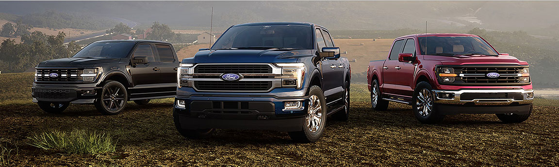 Three Ford F-150 full-size pickup trucks displayed in a scenic rural landscape