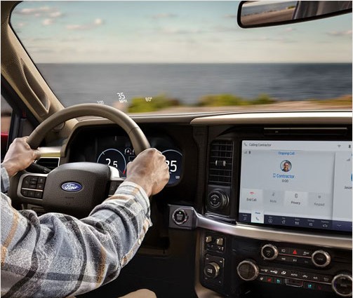 Driver behind the wheel of a Ford F-150 using the truck's touchscreen hands-free calling system