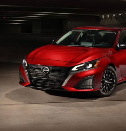 Red Nissan Altima sedan parked in dark parking garage