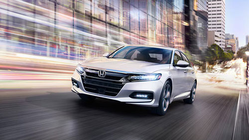 White Honda Accord sedan driving through city street