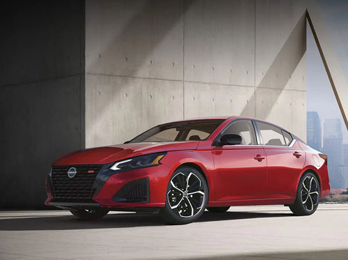 Red Nissan Altima sedan parked near concrete wall