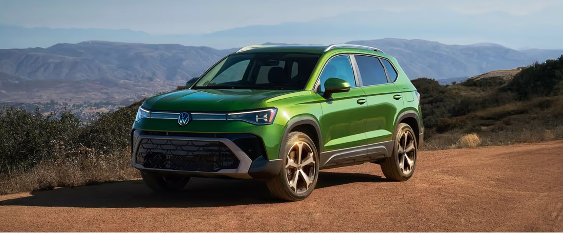 Green Volkswagen Taos SUV parked on a scenic mountain overlook