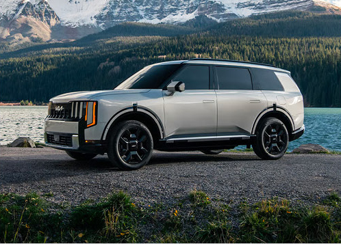 Kia Telluride SUV parked beside a mountain lake with scenic alpine views in the background.