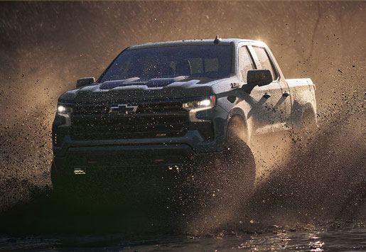 Chevrolet Silverado driving through mud during an off-road adventure