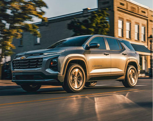 Silver Chevrolet Equinox driving through a downtown street